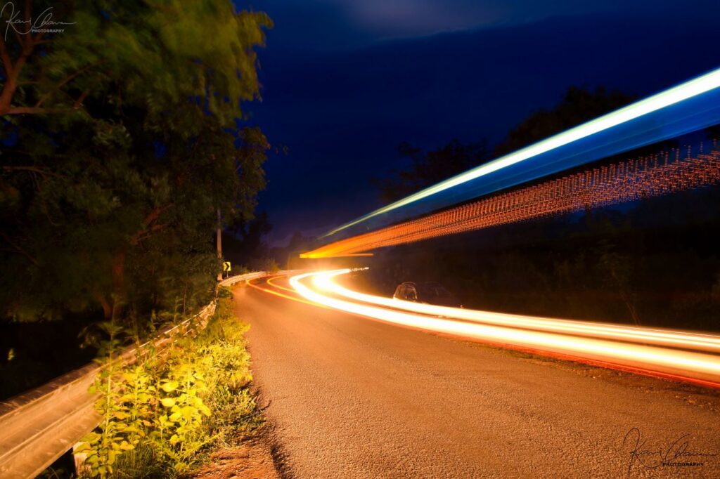 Light trail image of vehicles passing through forest near Manchanabele Dam